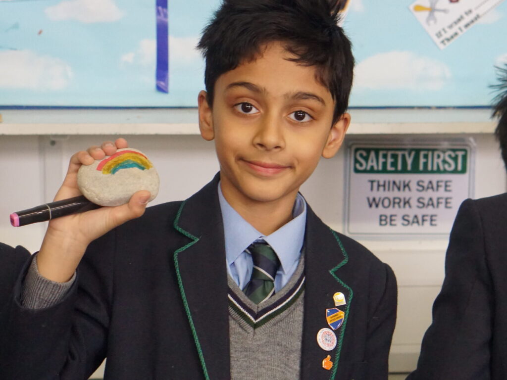 student holding a rock with a rainbow on it